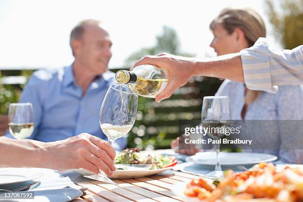 mann gießen wein im sonnigen tisch - wein trinken stock-fotos und bilder