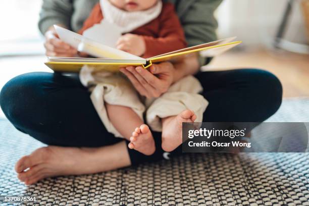 cropped shot of mother reading to baby - stories of the day stock-fotos und bilder