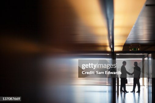 Businessman shaking hands together in corridor Businessman shaking hands together in corridor
