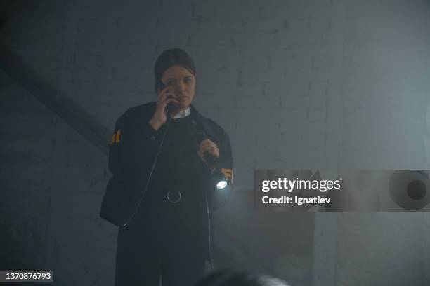 female fbi agent with a flashlight at the crime scene, calling criminologists on the phone - fbi warning stock pictures, royalty-free photos & images