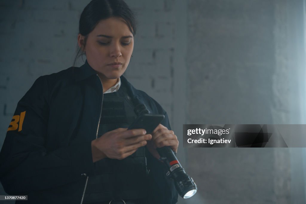 Female FBI agent with her smartphone at the crime scene in a day light
