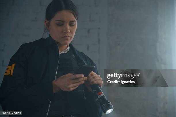 female fbi agent with her smartphone at the crime scene in a day light - female fbi stock pictures, royalty-free photos & images