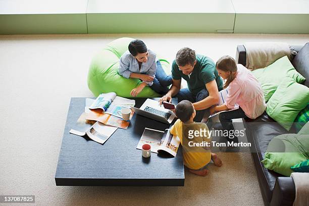 family using laptop together in living room - magazine table stock pictures, royalty-free photos & images