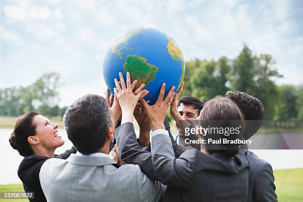 business people standing outdoors holding globe together - prop stock pictures, royalty-free photos & images