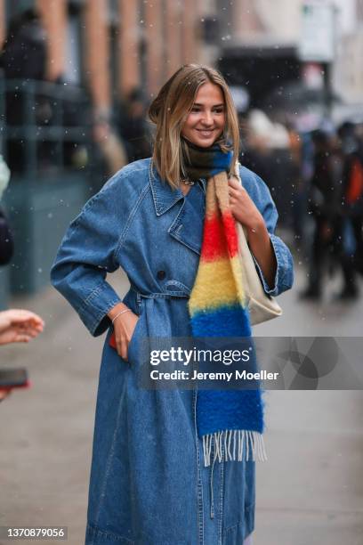 Mia Regan wears a blue jeans coat and a red / yellow / blue scarf outside Khaite during New Yorker Fashion Week on February 13, 2022 in New York City.