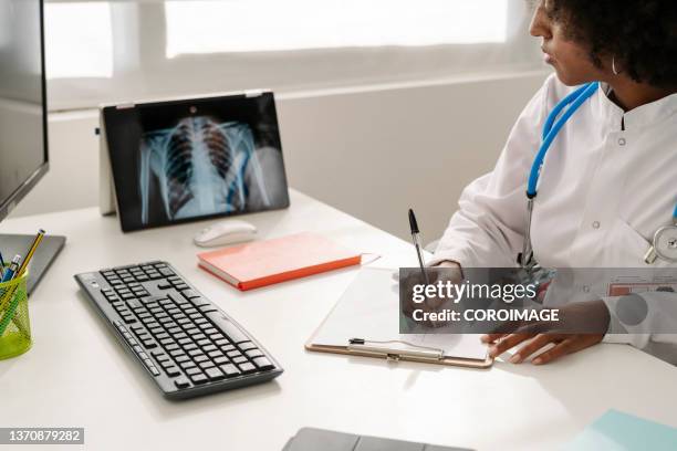 female doctor examining an x-ray picture on the digital tablet. - brustkorb stock-fotos und bilder