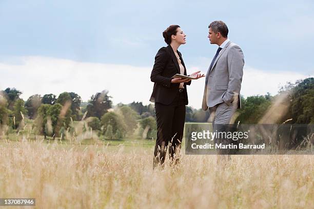business people talking together outdoors - low angle view of two businessmen standing face to face outdoors stock pictures, royalty-free photos & images