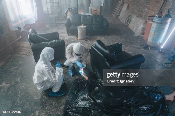 top view on criminologists in protective suits at the crime scene in abandoned warehouse in a daylight, examine the dead body on the floor - crime lab stock pictures, royalty-free photos & images