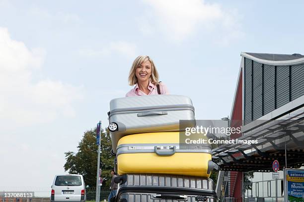 mid adult woman pushing luggage trolley to airport - luggage trolley stock pictures, royalty-free photos & images