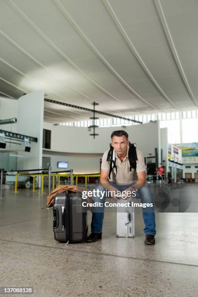 man sitzt auf koffer am flughafen - mittelalter mann stock-fotos und bilder