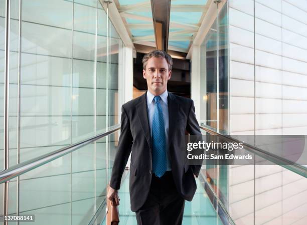 hombre de negocios caminando en puente peatonal de cristal - business man walking fotografías e imágenes de stock