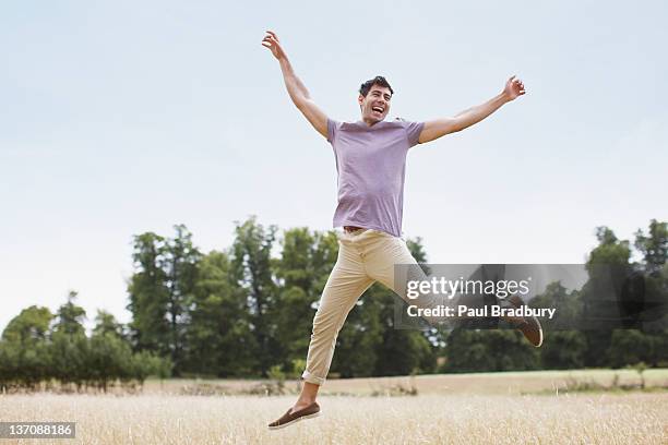 exuberante homem saltar no campo rural - jumping imagens e fotografias de stock