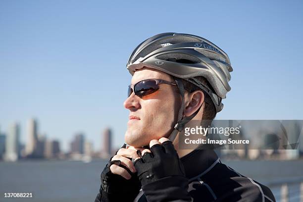 man adjusting bike helmet strap - sports helmet stock pictures, royalty-free photos & images