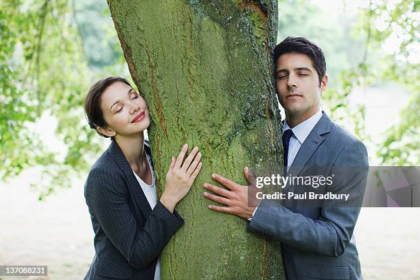 business people hugging tree - tree hugging stock pictures, royalty-free photos & images