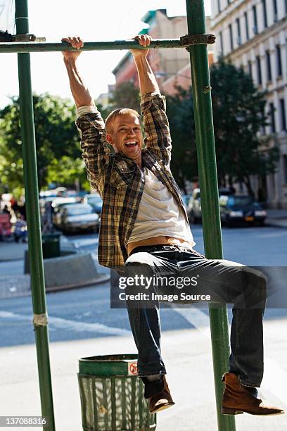 mid adult man hanging from street lamp post - street light post stock pictures, royalty-free photos & images