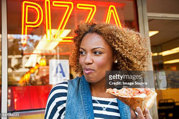 young woman eating pizza slice - pizza slice stock pictures, royalty-free photos & images