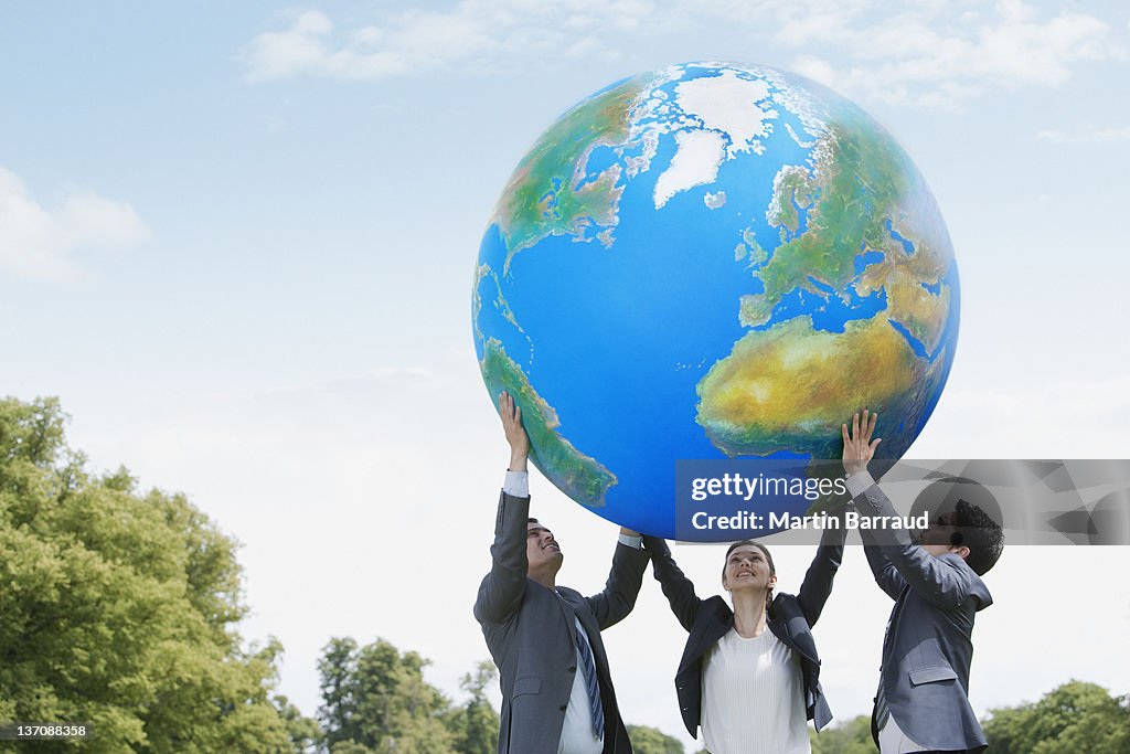 Business people lifting large ball together