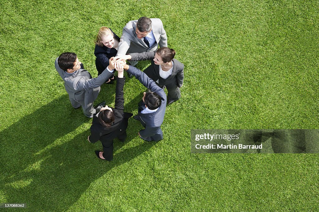 Business people standing in circle holding hands