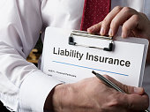 Hands hold liability insurance policy and pen.