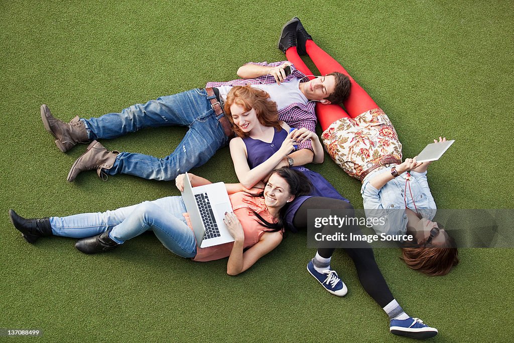 Four people lying down with a laptop, digital tablet and mobile phone
