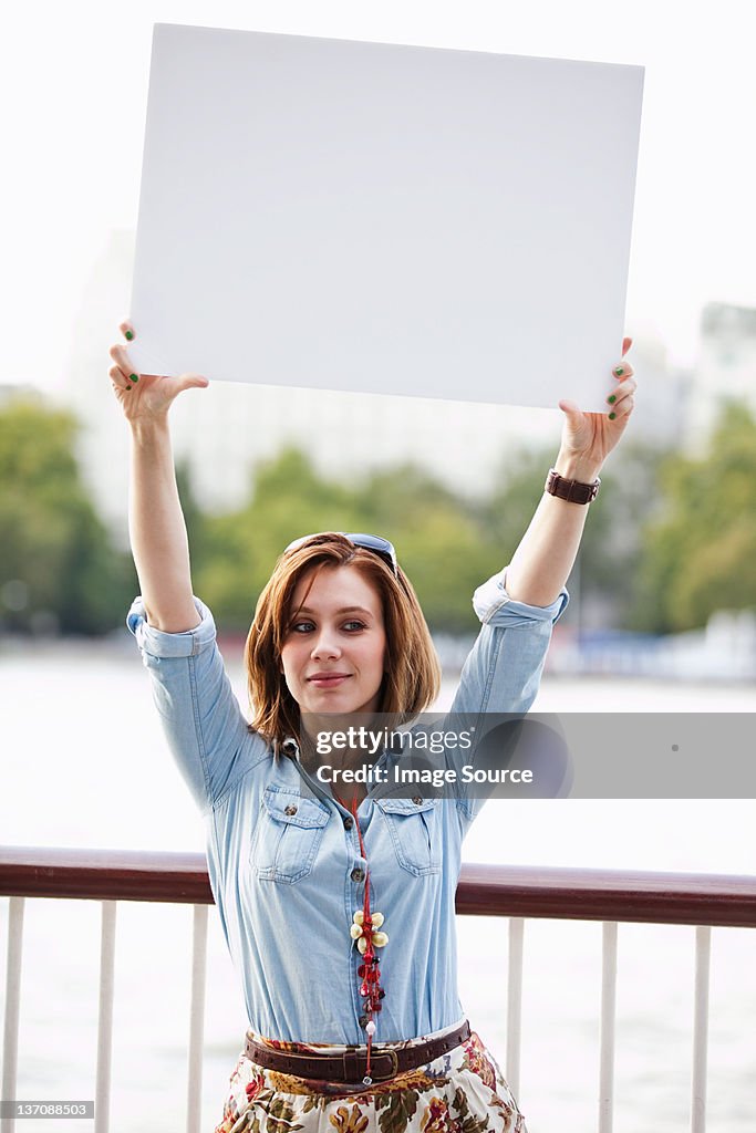 Young woman holding up a white board