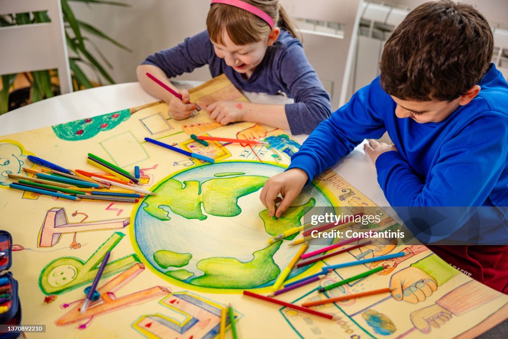 Creative Caucasian children, drawing and coloring the paper with planet Earth in order to raise sustainable lifestyle