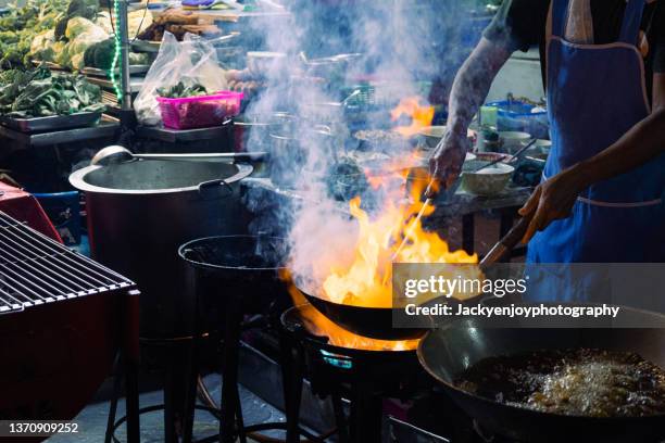 street food cooking in chinatown street or yaowarat road at night time, bangkok, thailand - cuisine de rue photos et images de collection