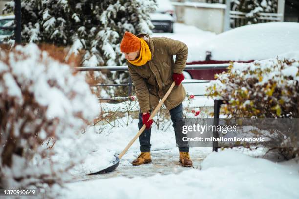 hombre limpiando nieve en un patio - spade fotografías e imágenes de stock