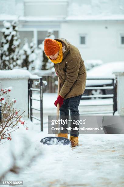 junger mann räumt schnee vom weg zu seinem gebäude - city cleaning stock-fotos und bilder