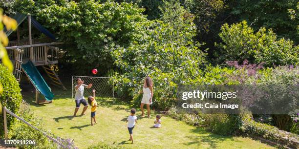 family playing soccer in sunny summer backyard - backyard football stock-fotos und bilder