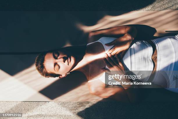 graceful slim woman trainer in white sportswear practices yoga exercises on floor mat. - zen foto e immagini stock