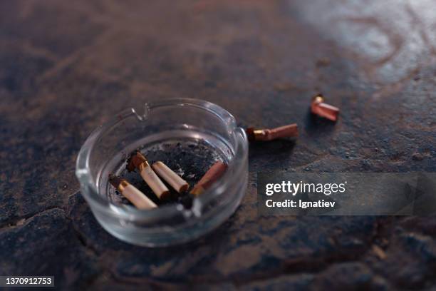 an ashtray with cigarette butts on the dark floor - ashtray stock pictures, royalty-free photos & images