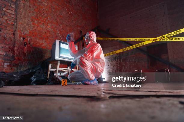 perspective view on abandoned warehouse where the den of criminals was located before the crime and a criminologist working at the crime scene - forsaken film stockfoto's en -beelden