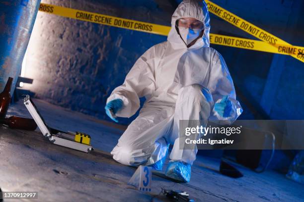 criminologist in protective suit at the crime scene in blue illumination - criminology stock pictures, royalty-free photos & images