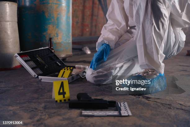 criminologist  in protective suit with one knee on the floor next to the criminologist's kit, only a body is in the frame without head - criminology stock pictures, royalty-free photos & images
