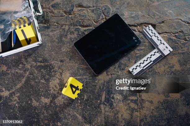 a digital tablet on a stoned floor at the crime scene with a number of physical evidence - crime scene stock pictures, royalty-free photos & images