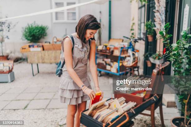 girl choosing book from bookstore at the street - bookstand stock pictures, royalty-free photos & images