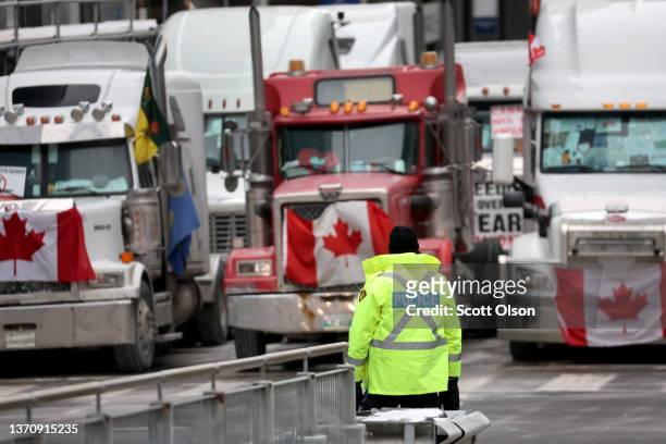 Police officer stands guard near trucks participating in a blockade of downtown streets near the parliament building as a demonstration led by truck...