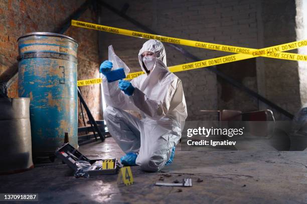 criminologist in a protective suit with holding physical evidence - coroner stockfoto's en -beelden