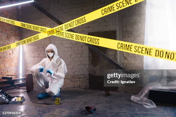 criminologist behind the barricade tape, working in abandoned warehouse - murderer stock pictures, royalty-free photos & images