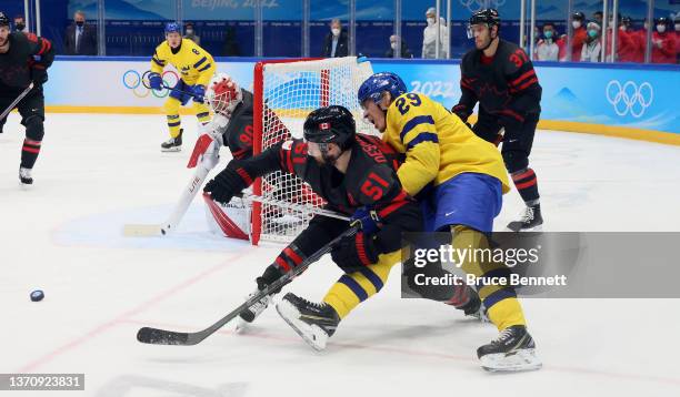 Forward David Desharnais of Team Canada and defender Pontus Holmberg of Team Sweden fight for control of the puck during the Men’s Ice Hockey...
