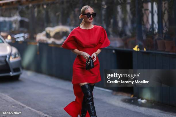 Leonie Hanne wearing a red dress, a black bag outside Carolina Herrera during New York Fashion Week on February 14, 2022 in New York City.