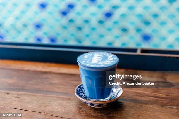 blue butterfly pea latte with latte art served in a coffee shop - clitoria fotografías e imágenes de stock