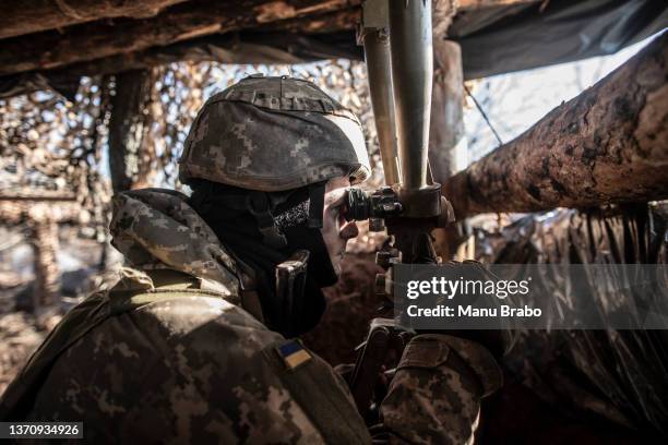 An Ukrainian serviceman watches DPR rebel's positions from a trench at the contact line near the village of Svitlodarsk, in Donestsk region on...
