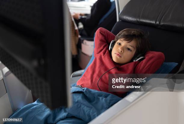 junge, der einen film im flugzeug sieht, während er in der ersten klasse reist - first class plane stock-fotos und bilder