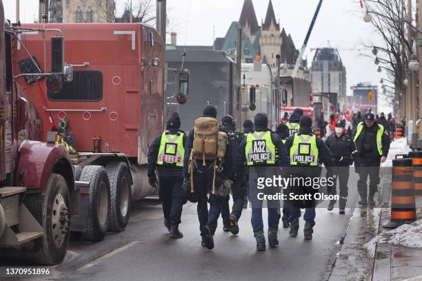 Police patrol past a blockade of trucks near the parliament building as a demonstration led by truck drivers protesting vaccine mandates continues on...