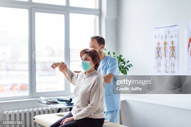 physical therapist helping senior woman with her shoulders - hospital quarantine stock pictures, royalty-free photos & images