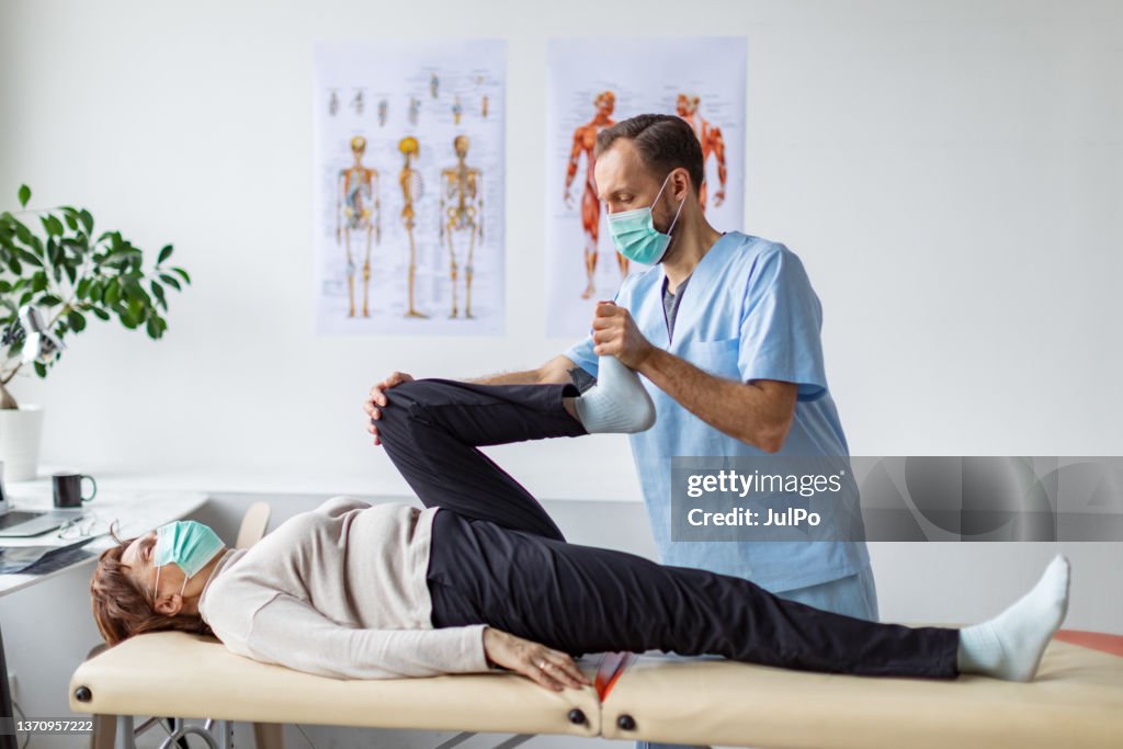Physical therapist helping senior woman with exercise for legs