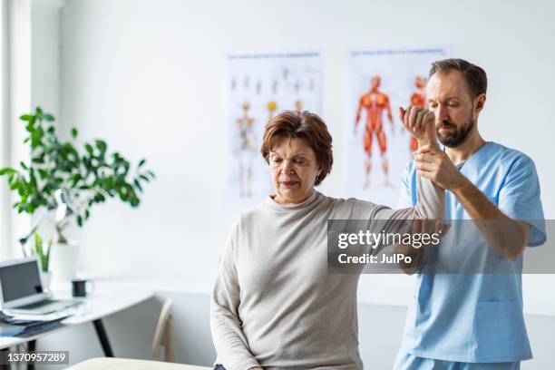 physical therapist helping senior woman with her shoulders - arm pain stock pictures, royalty-free photos & images