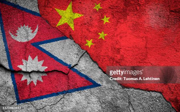 full frame photo of weathered flags of nepal and china painted on a cracked wall. - nepali flag stockfoto's en -beelden